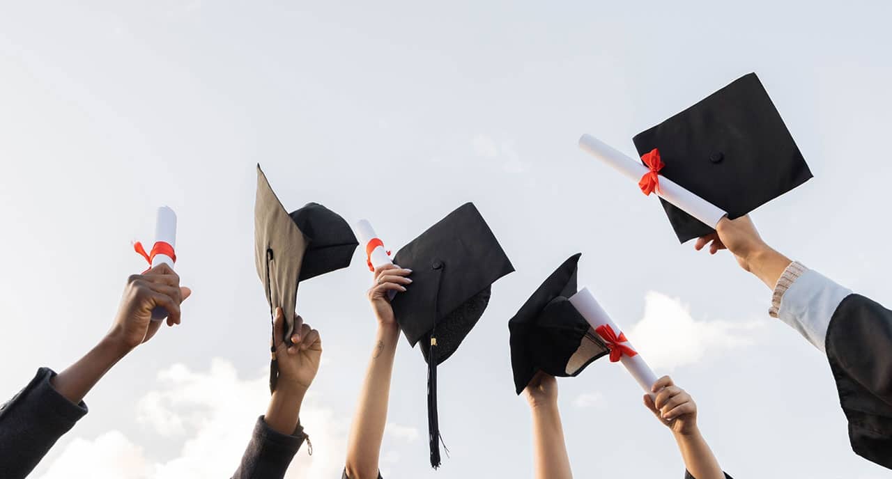 Graduation certificate and hands raised in sky